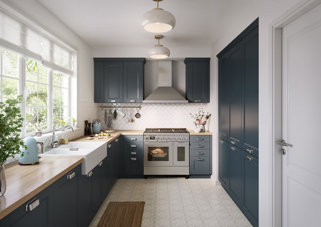 Cuisine fonctionnelle avec meubles bleu foncé style shaker, plan de travail en bois clair, évier de style farmhouse, crédence en carreaux blancs motif chevrons et grand piano de cuisson en inox.