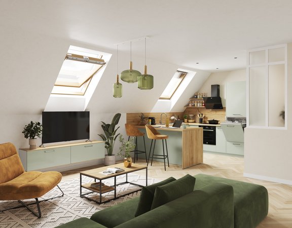 Pièce de vie aménagée sous combles (mansarde) avec cuisine et mobilier bas vert d'eau, canapé velours vert sapin, fauteuil ocre et éclairage naturel par lucarnes de toit.