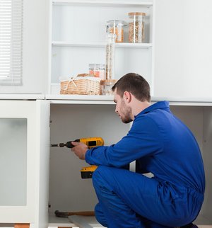 Keukenmonteur plaatst kast met boormachine
