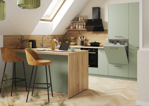 Petite cuisine moderne sous les toits, caractérisée par des façades vert sauge, un plan de travail en bois clair et une fenêtre de toit pour une luminosité optimale.