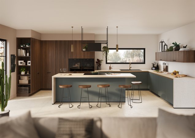 Cuisine moderne ouverte et lumineuse, intégrant un îlot central avec coin repas. Les façades combinent des tons de bois chaud et un vert-de-gris contemporain.